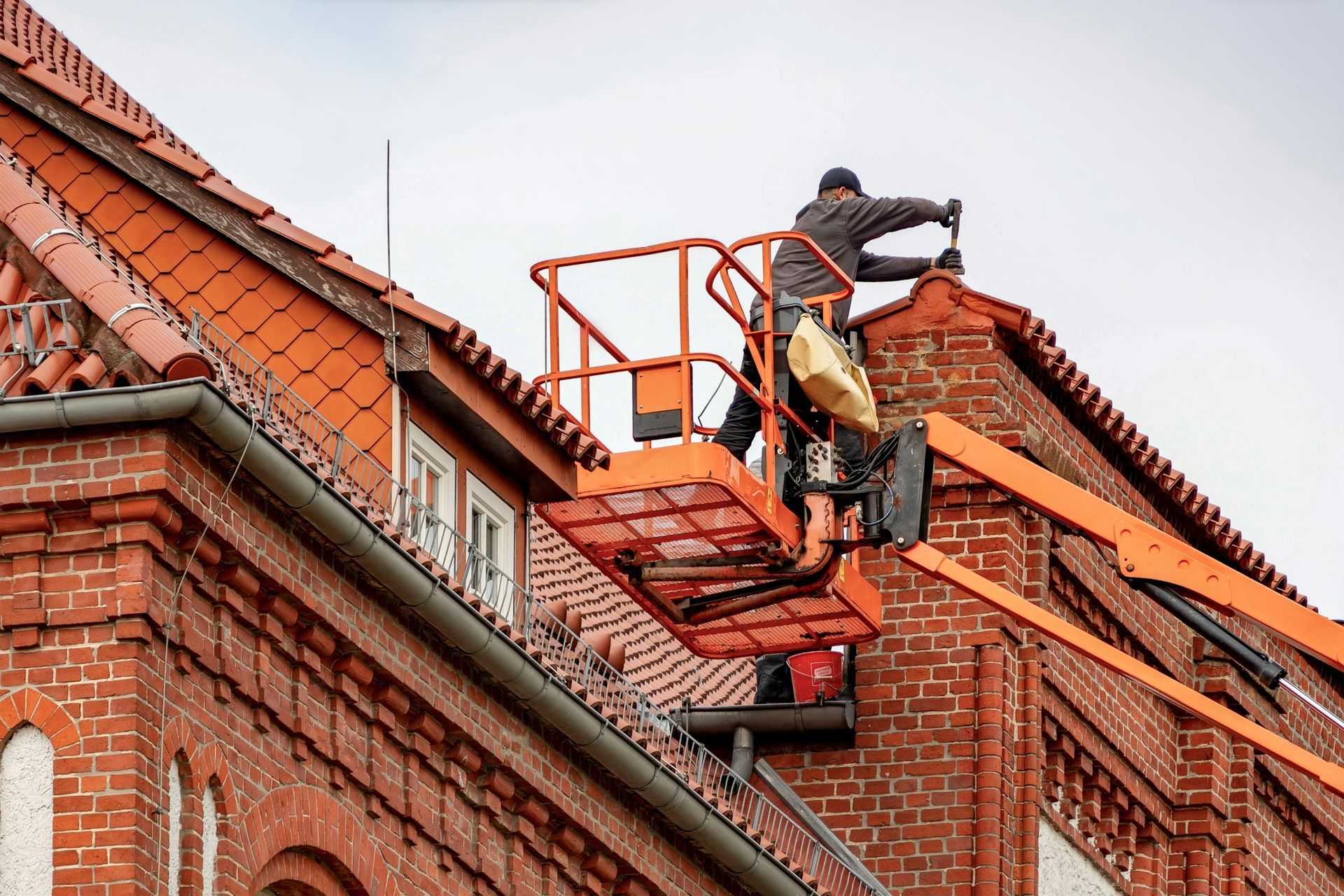 A man is working on the roof of a brick building.