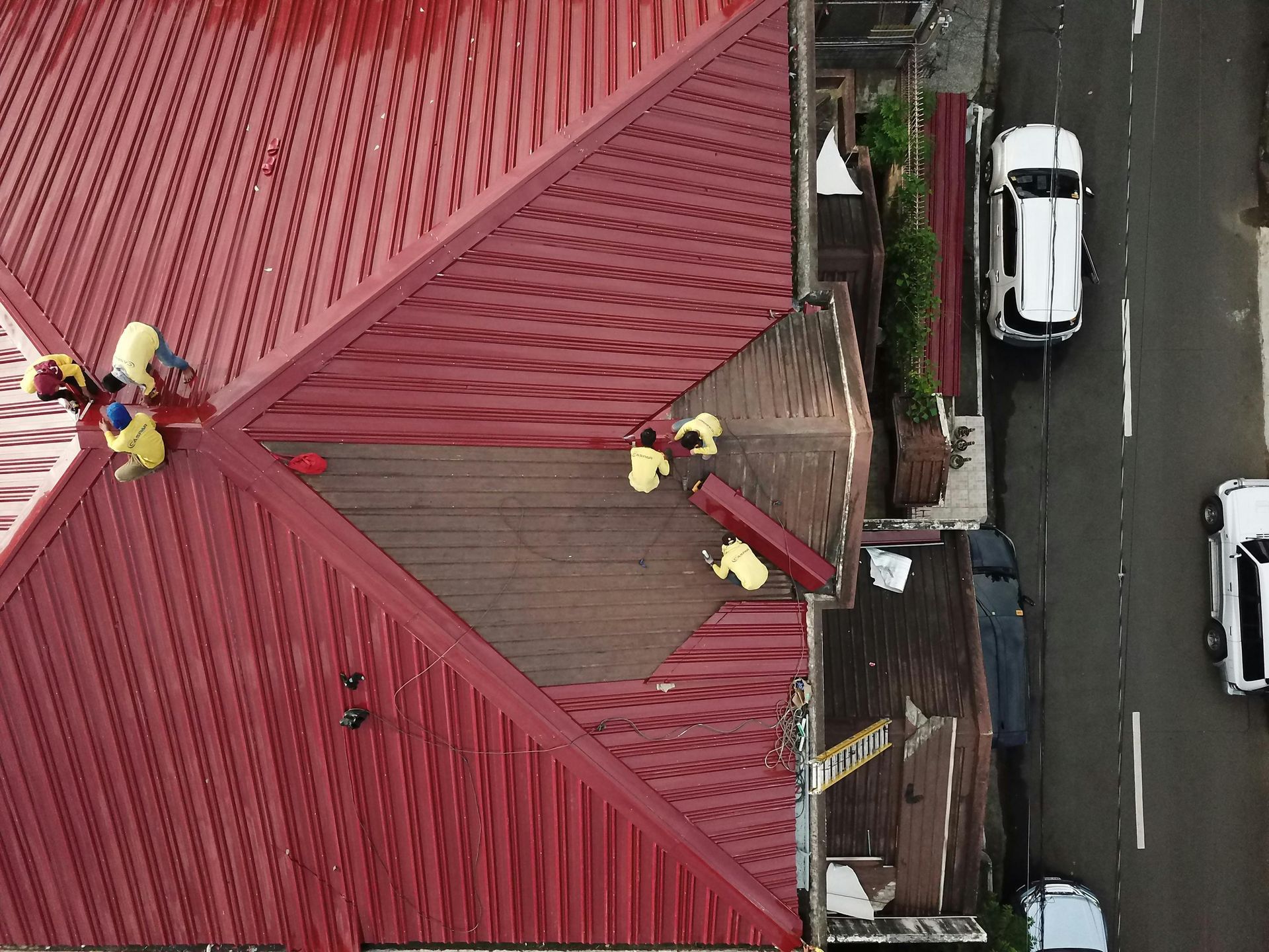 An aerial view of a red roof with people working on it.