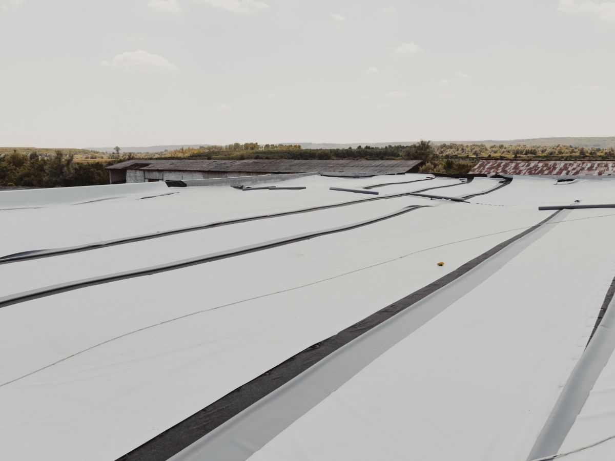 Aerial view of a white rooftop with black lines and a small orange ball, under a bright sky.