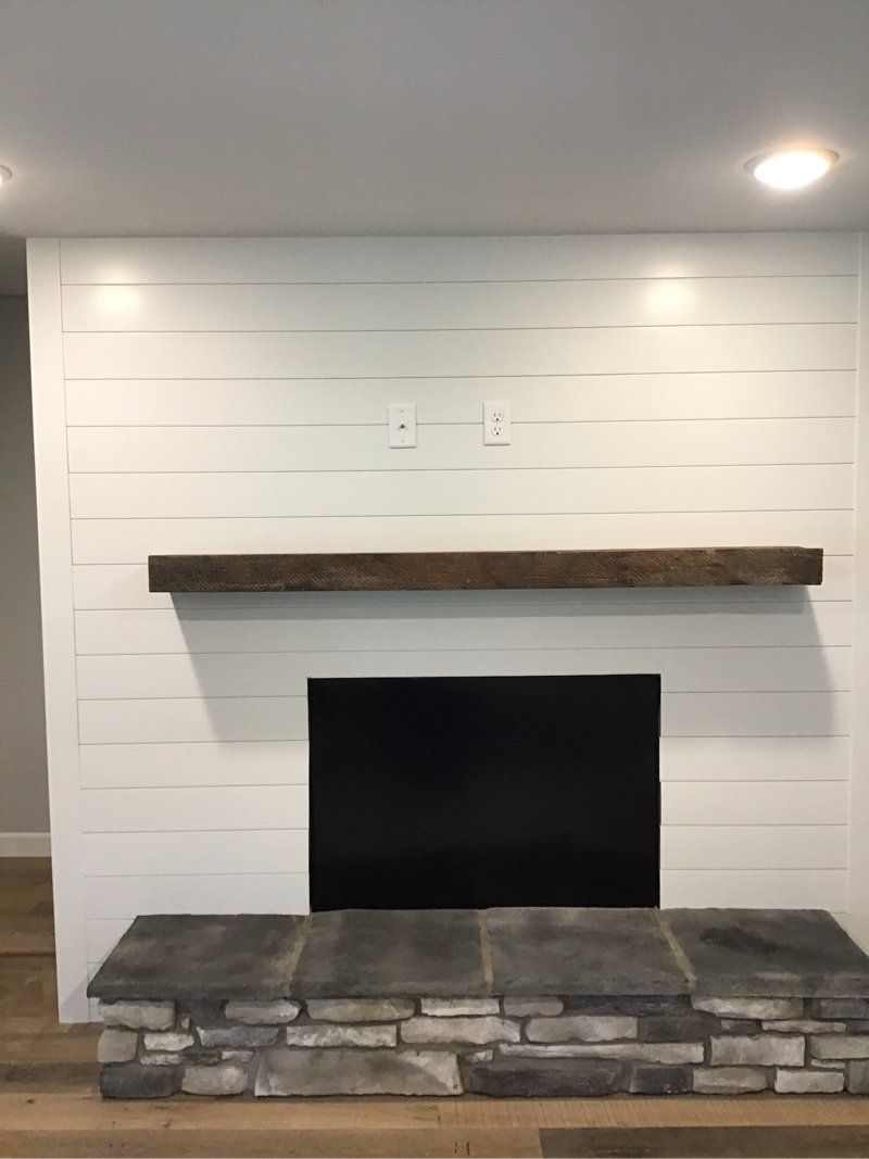 A living room with a fireplace and a wooden mantle.