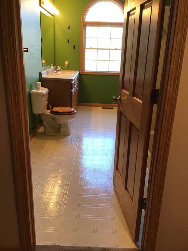 A bathroom with a toilet , sink , mirror and window.