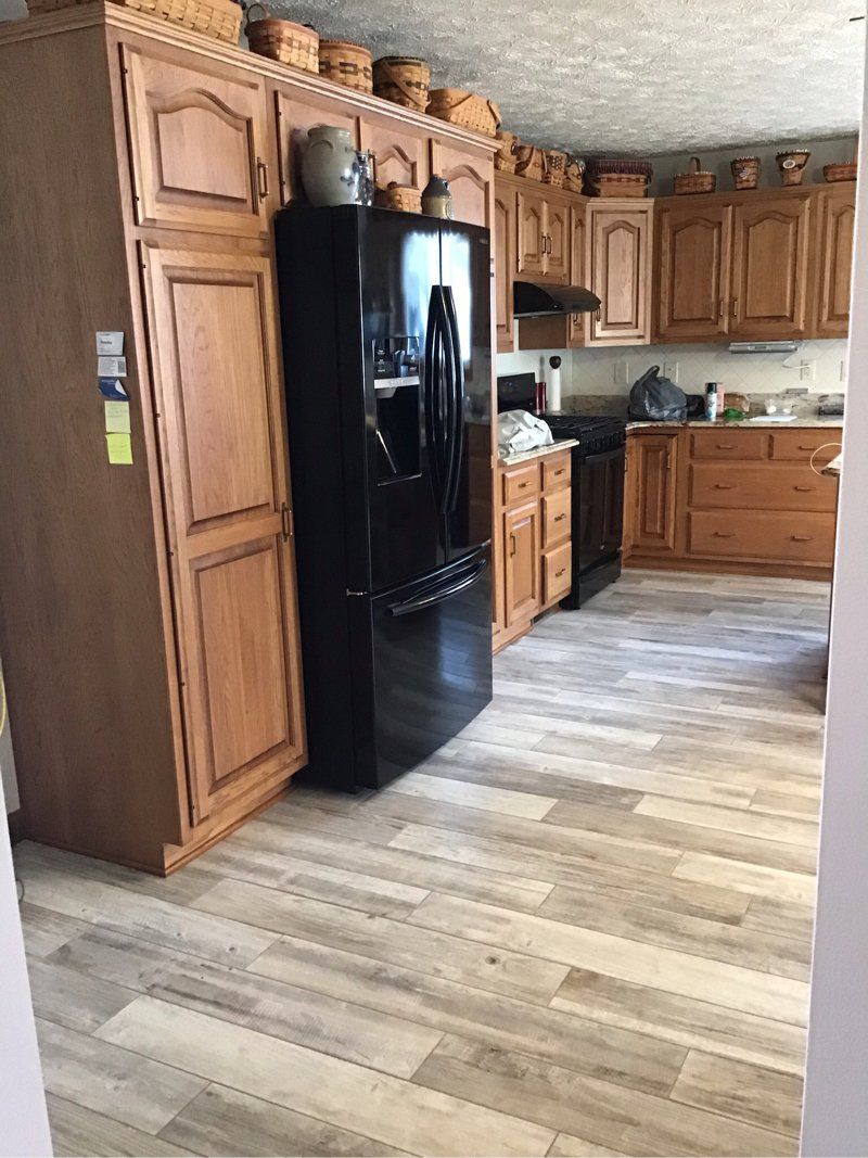 A kitchen with wooden cabinets and a black refrigerator.