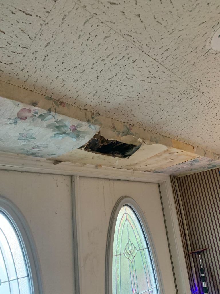 A room with a ceiling that is water damaged. 