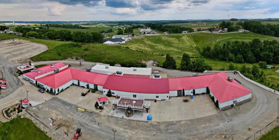 An aerial view of a large building with a red roof in the middle of a field.
