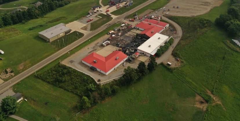 An aerial view of a large building with a red roof in the middle of a field.