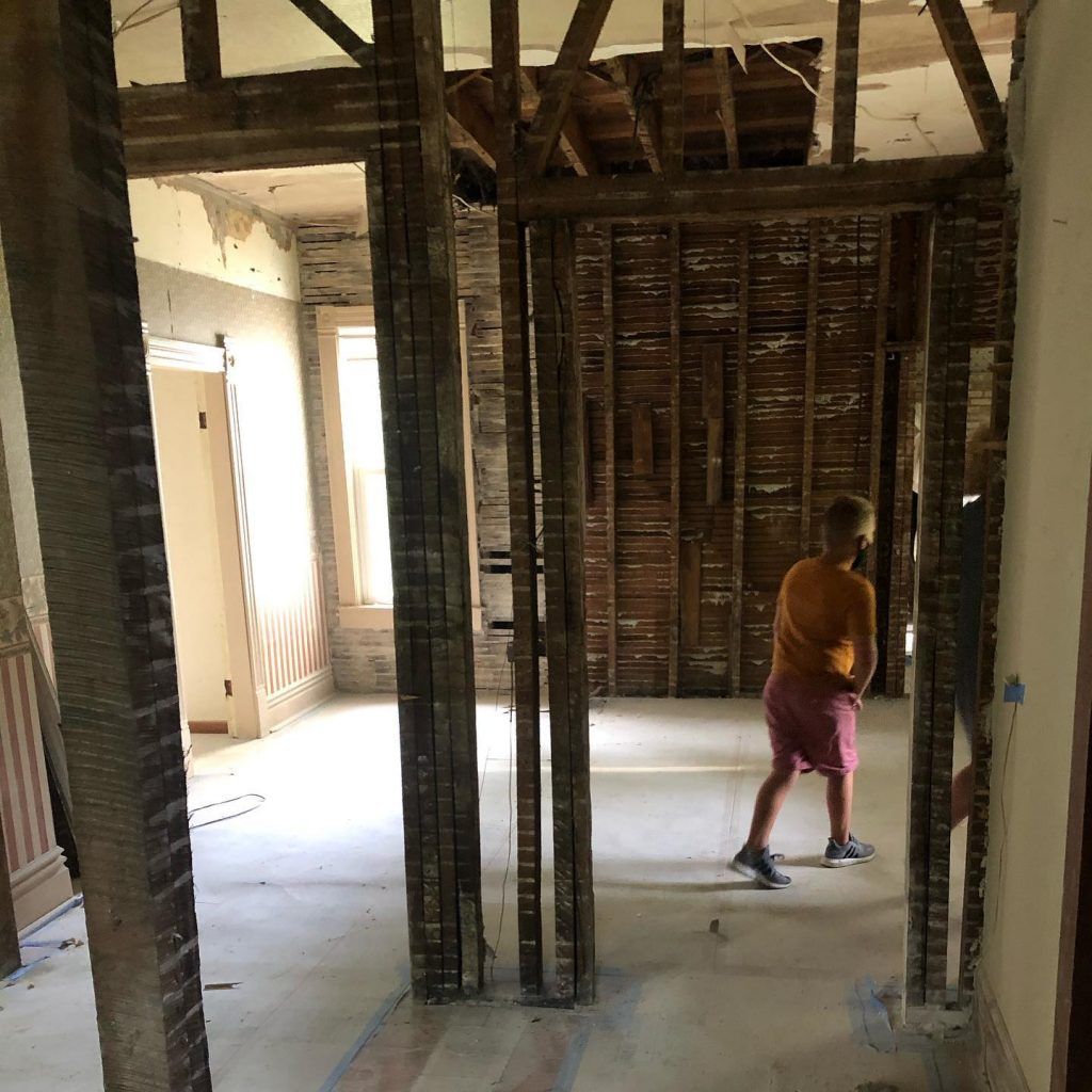 A boy standing in a room with wooden beams that is being remodeled.