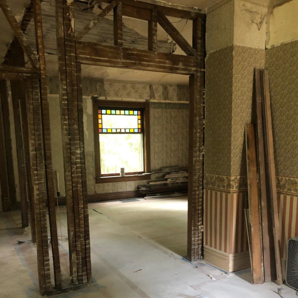 A room with a stained glass window and wooden beams being remodeled.