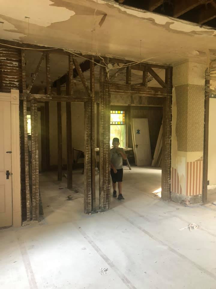 A boy is standing in a room that is being remodeled.