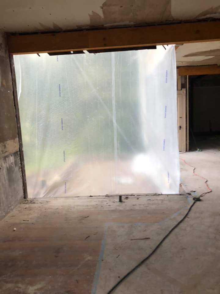 An empty room being remodeled with a clear plastic sheet on the wall.