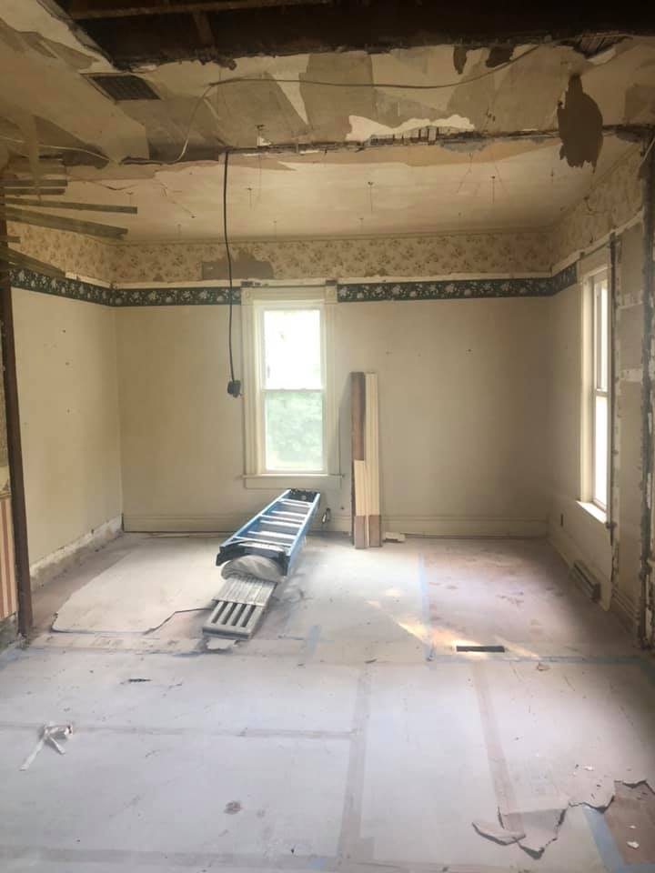 A room with a ladder on the floor and a window is being remodeled.