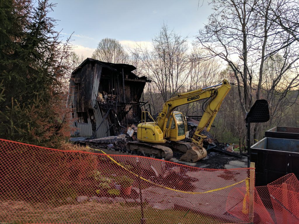 I excavator beside fire damaged structure.