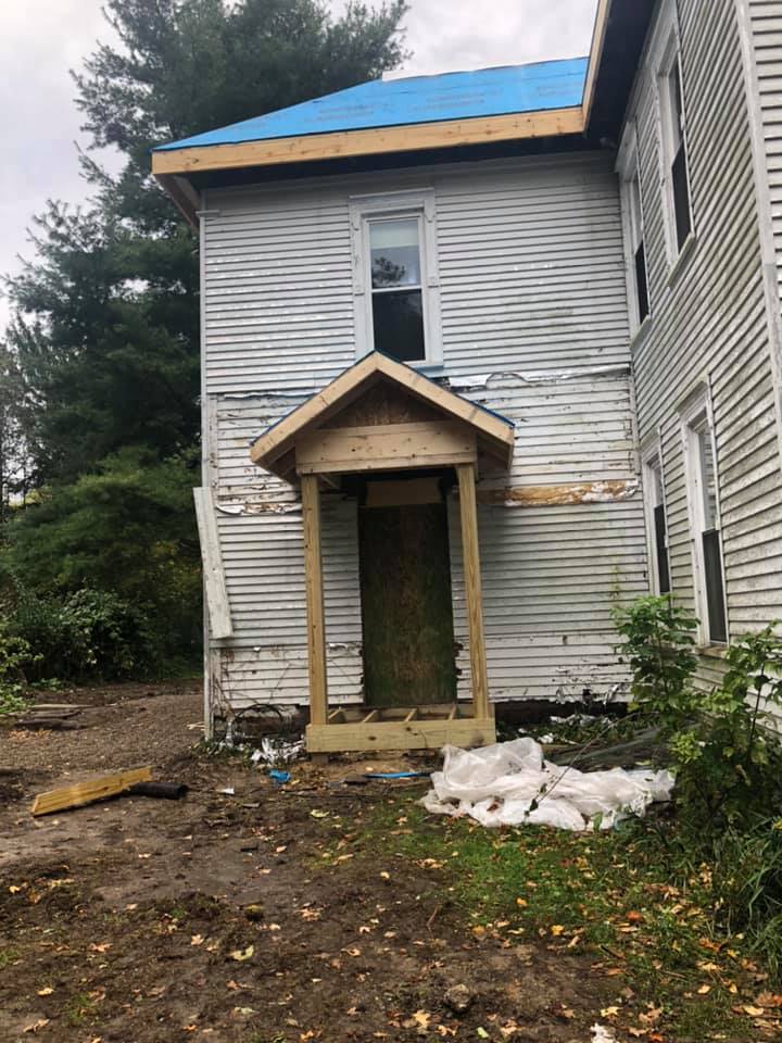 A white house with a blue roof is being remodeled.