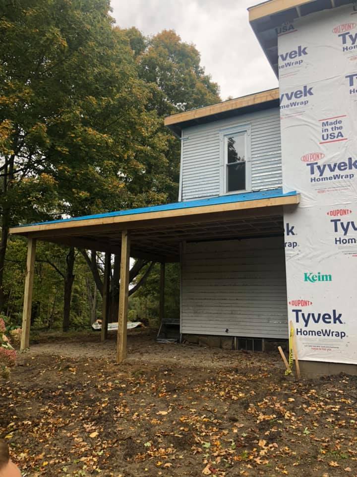 A house under construction with a blue roof and a wooden deck.