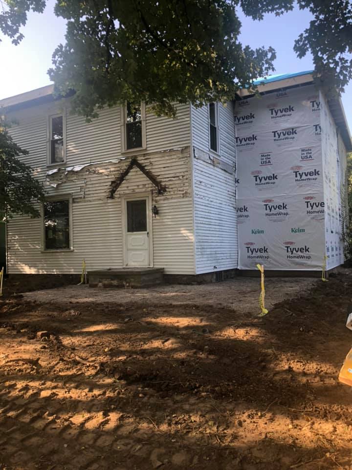 A white house with a blue roof is being remodeled.