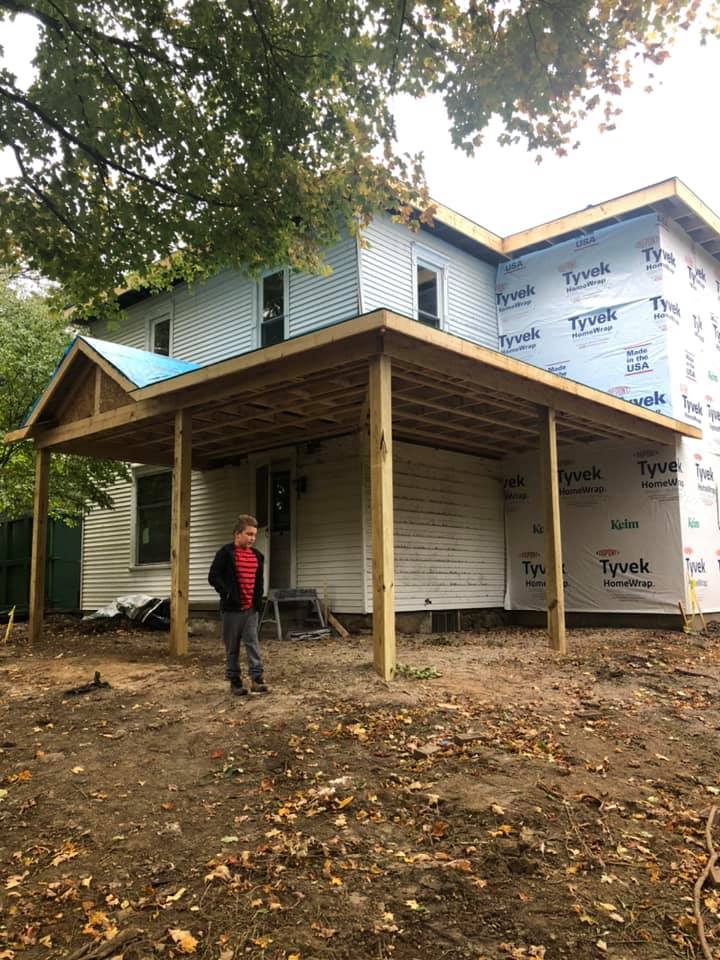 A man is standing in front of a house under construction.