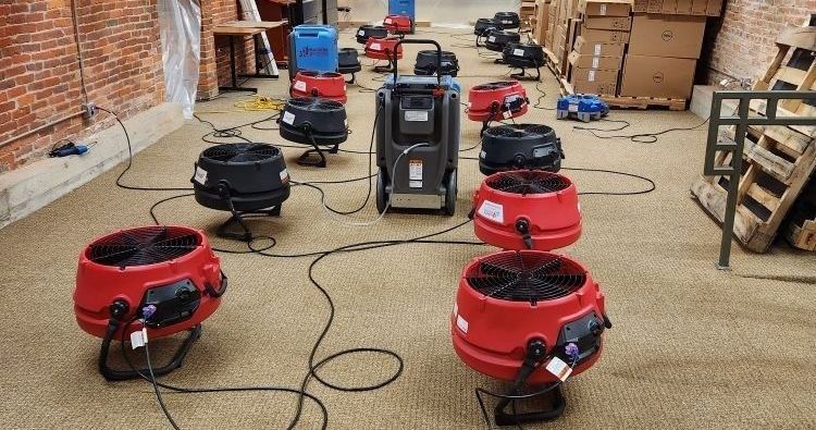 A row of red fans are lined up in a warehouse.