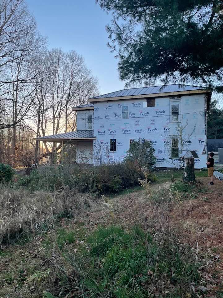 A large white farmhouse being remodeled.