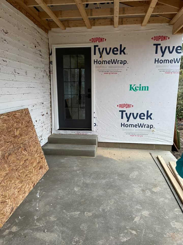 A home under construction with a door and stairs.