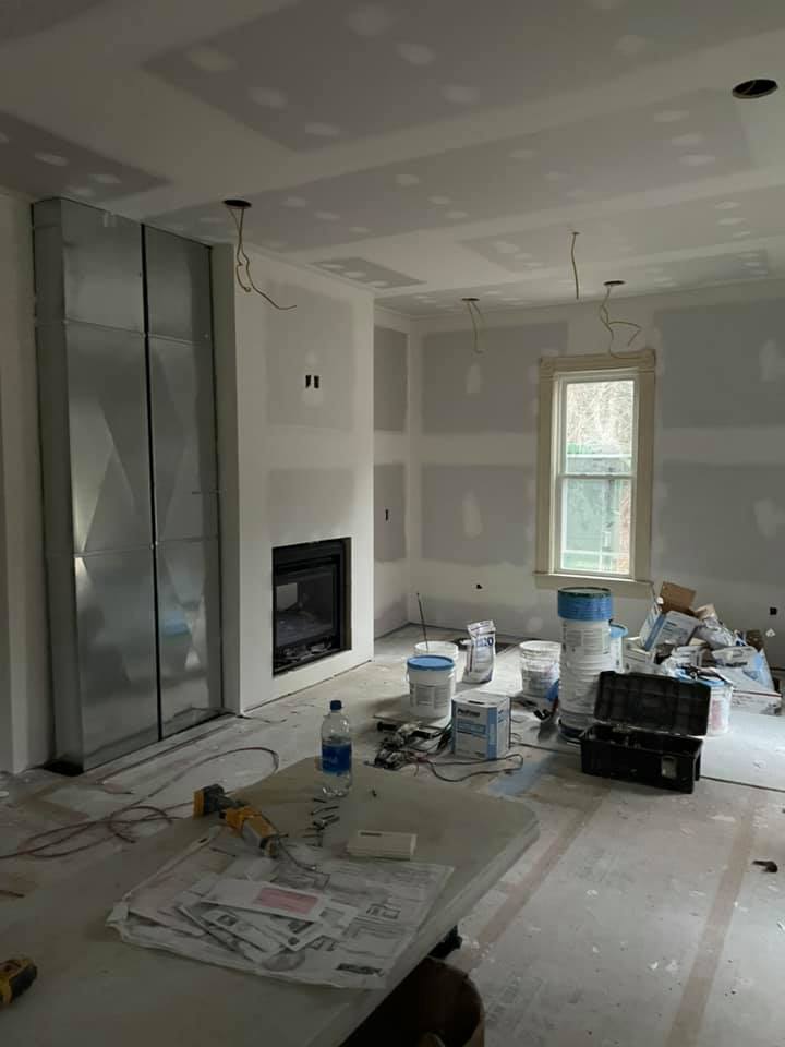 A living room being remodeled with a fireplace, table, and buckets of paint on the floor.
