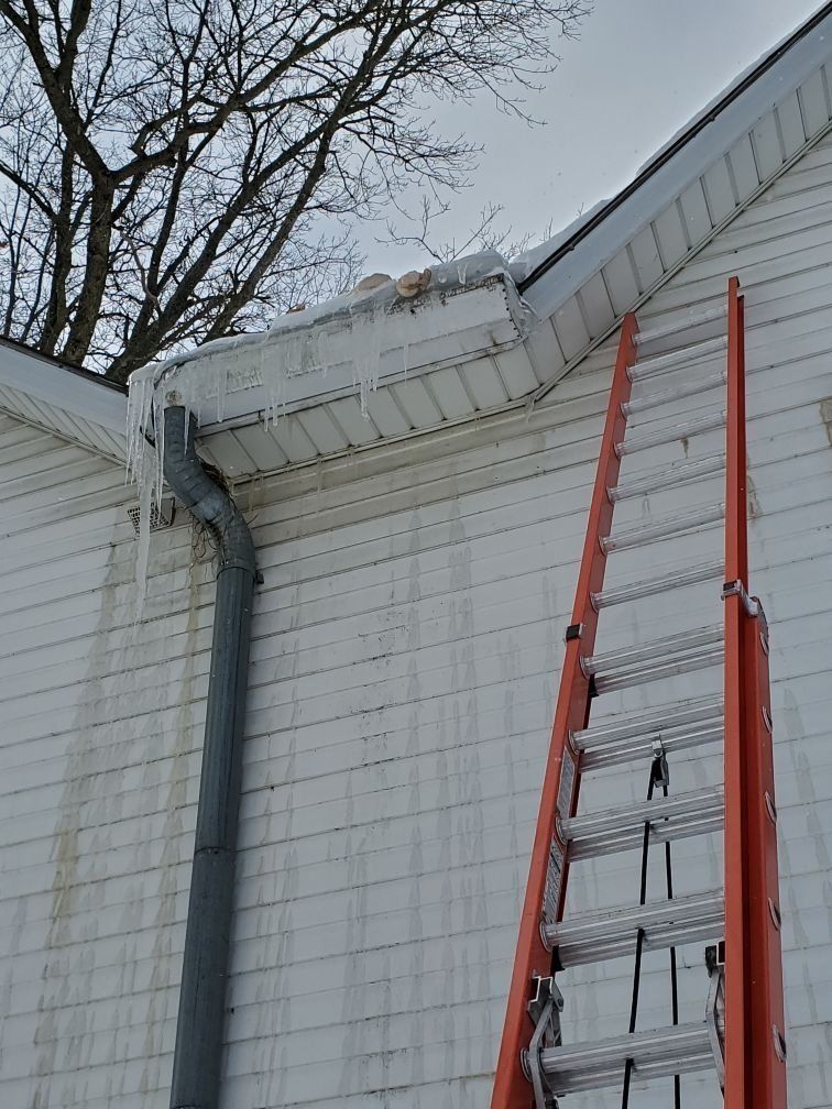 A ladder is leaning against the side of a white house.