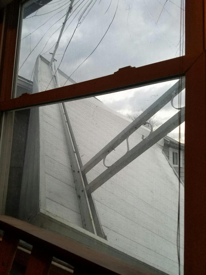 A patio roof has fallen onto house from wind damage.  