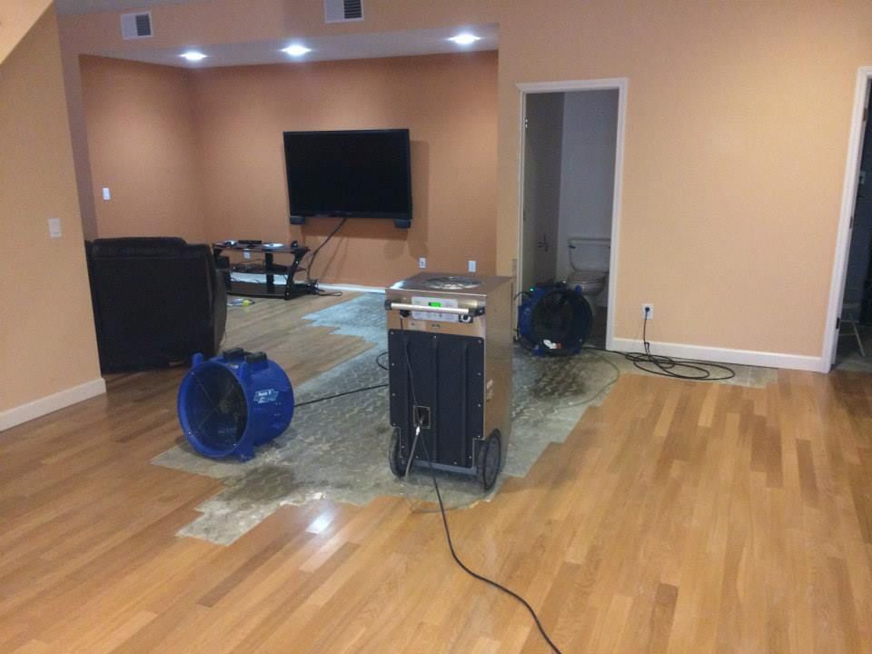 A living room with hardwood floors, a flat screen tv and industrial machines. 