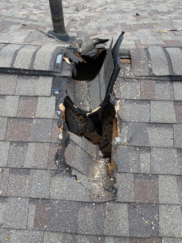A roof with a hole in it and shingles missing.