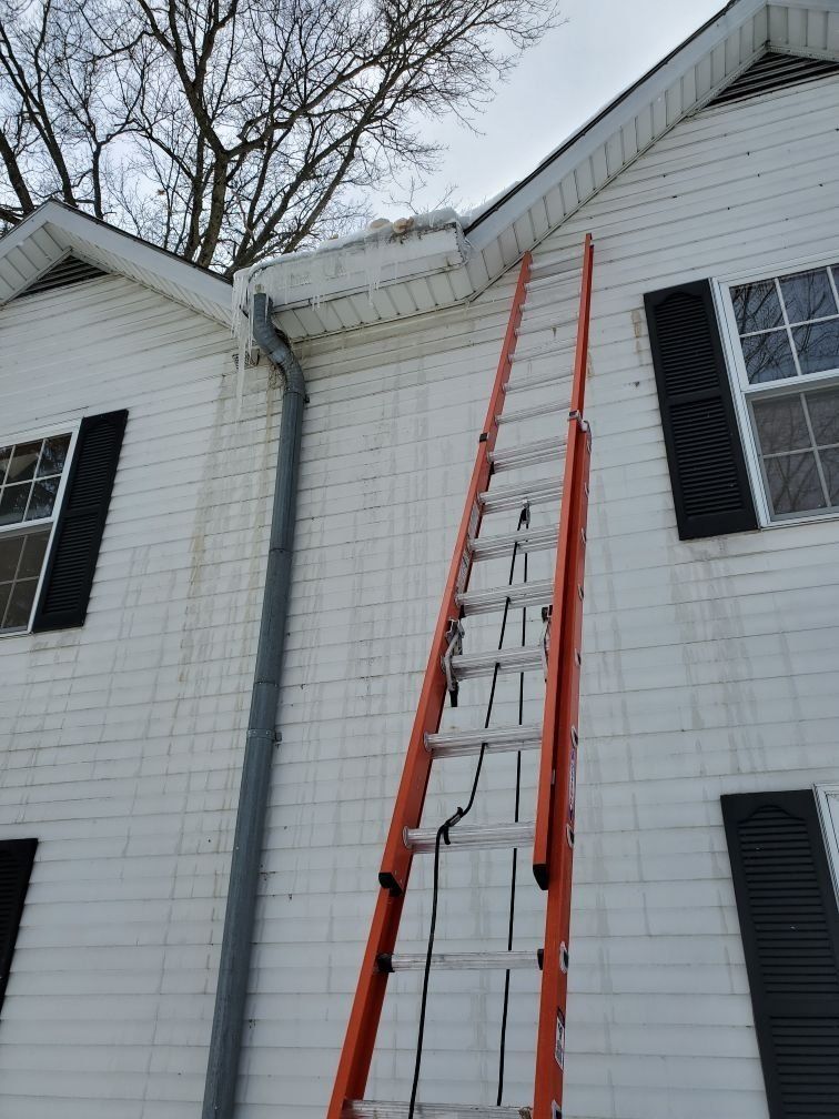 A ladder is leaning against the side of a white house.