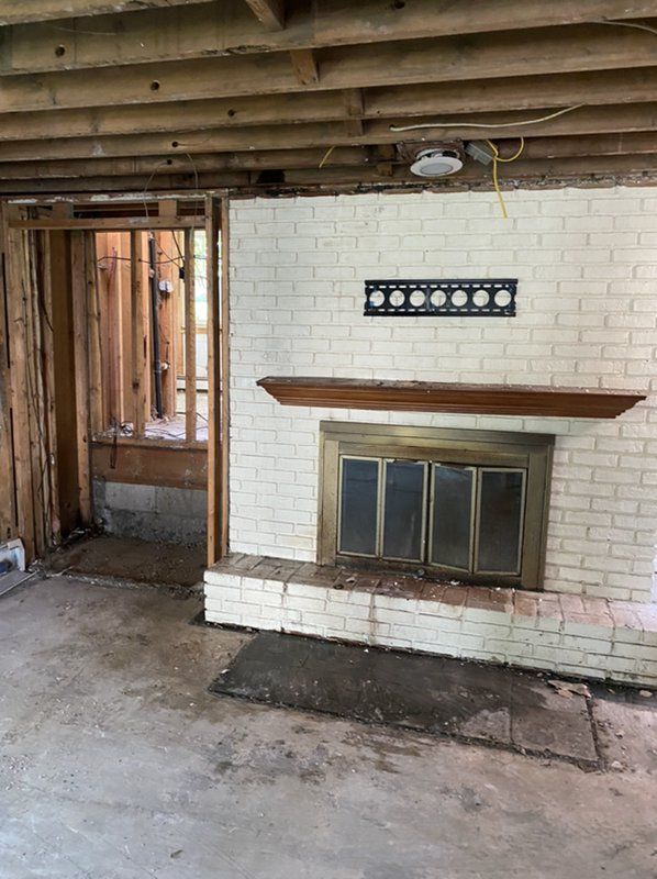 An empty room with white brick and a fireplace.