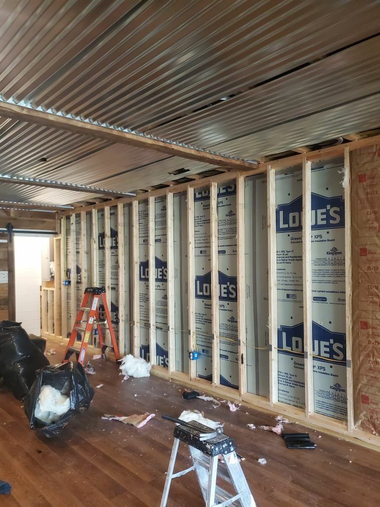 A room being repaired from chimney fire with a lot of wooden walls and a ladder on the floor.