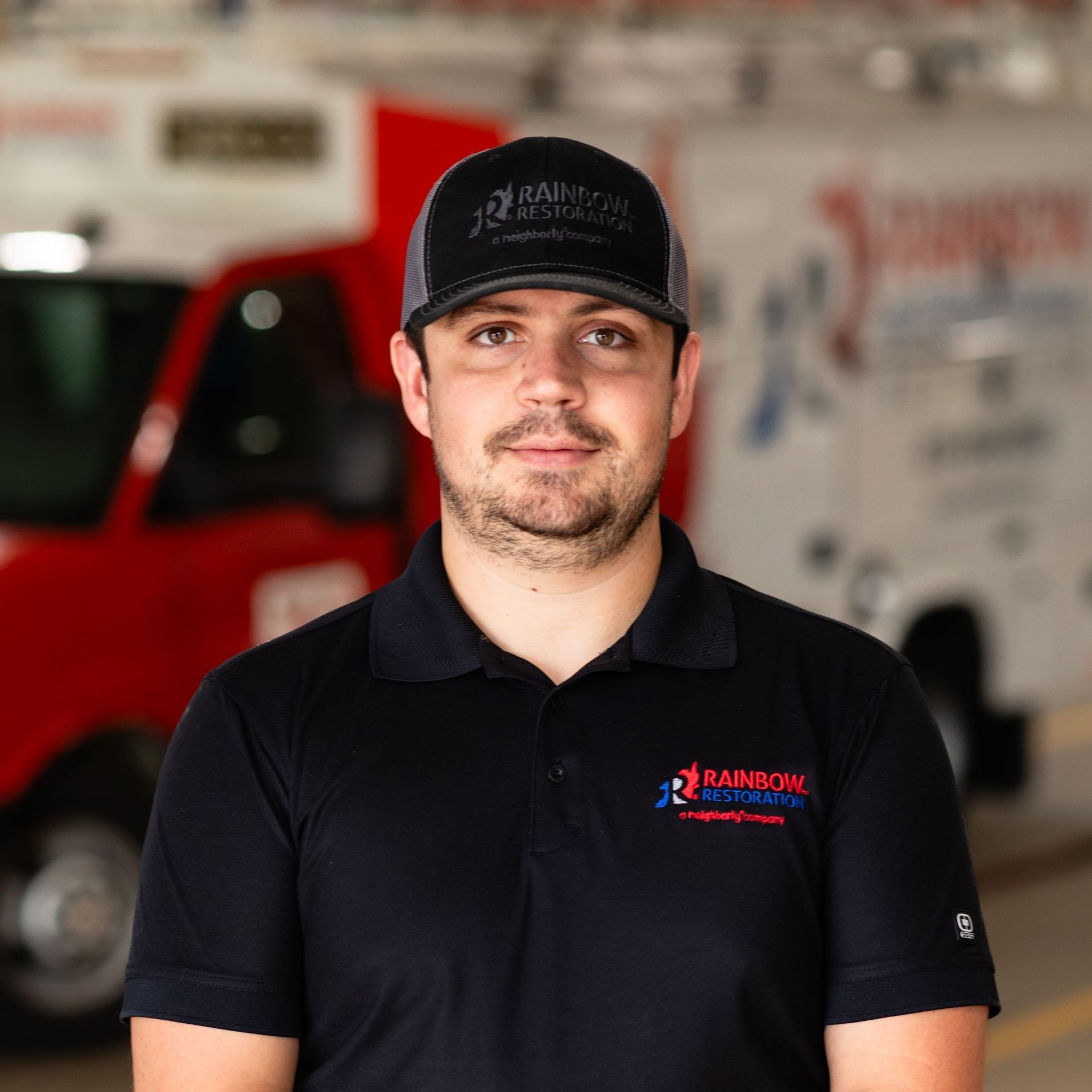 A man wearing a hat and a polo shirt is standing in front of an ambulance.