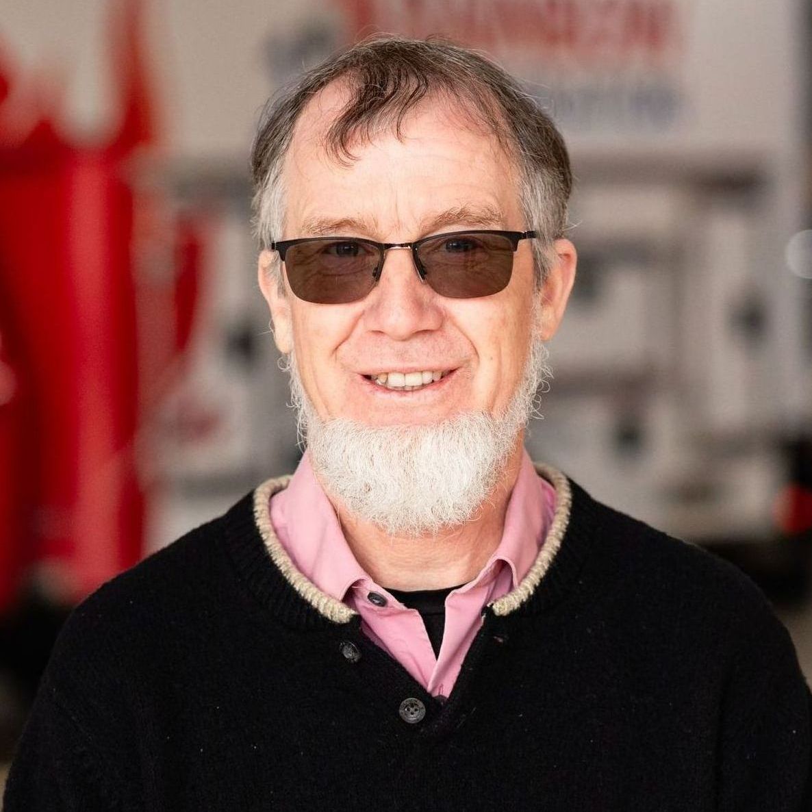 A man with a beard and sunglasses is smiling for the camera.
