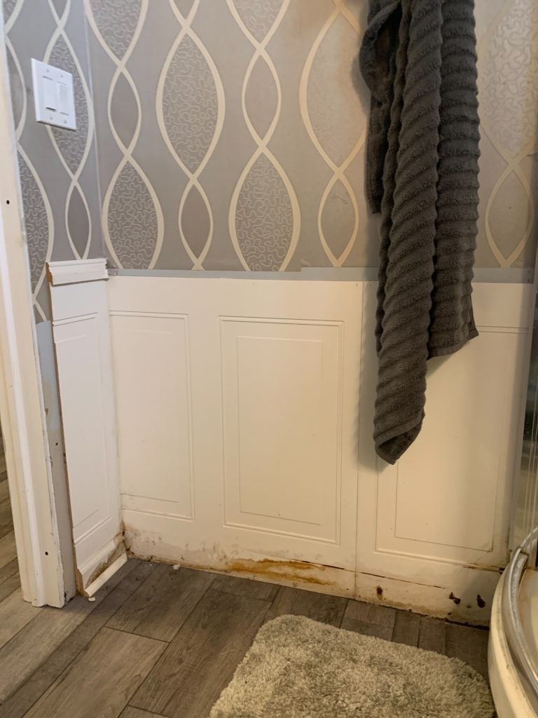 A bathroom with a towel hanging on the wall and a rug on the floor.