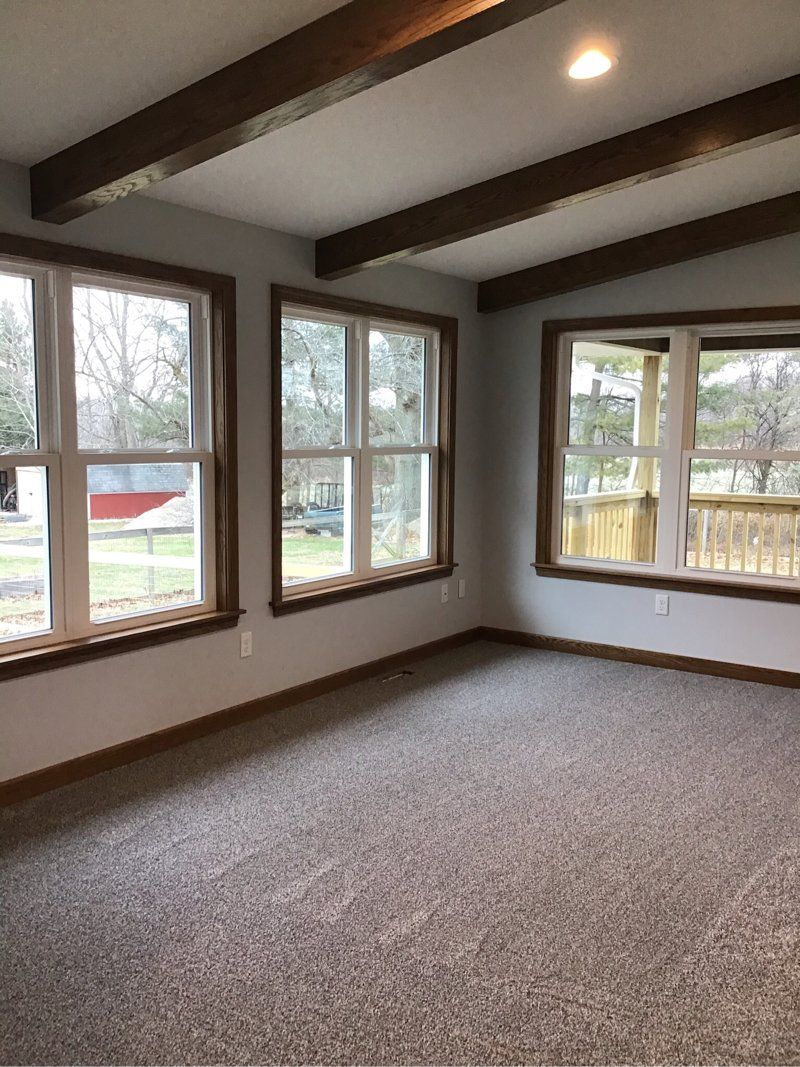 A living room with a lot of windows and a carpeted floor.
