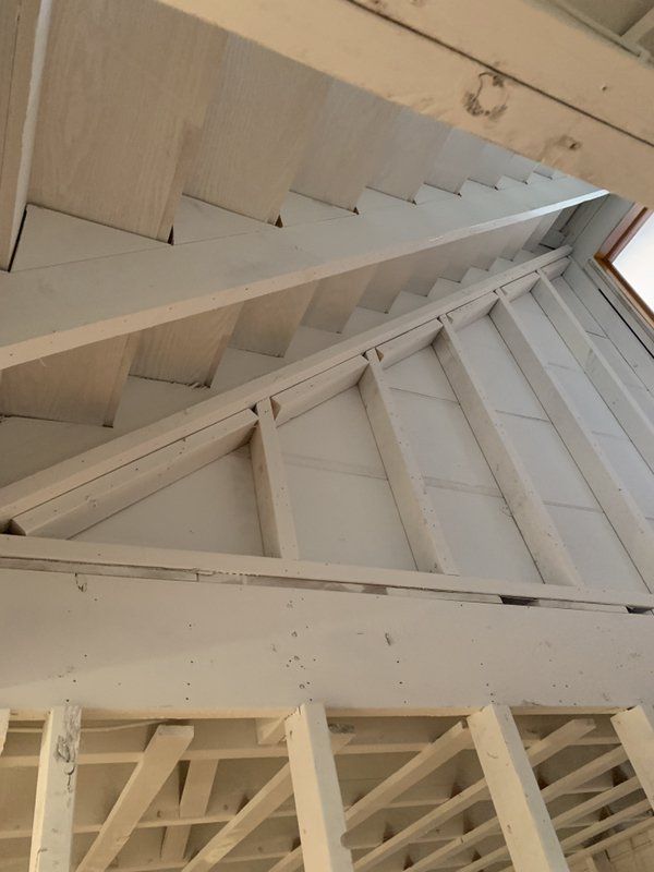 Looking up at the ceiling of a building with white beams