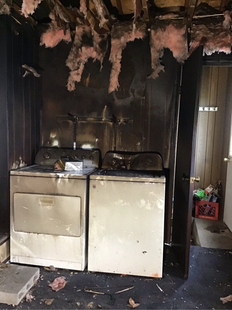 A smoke damaged laundry room with a washer and dryer in it.