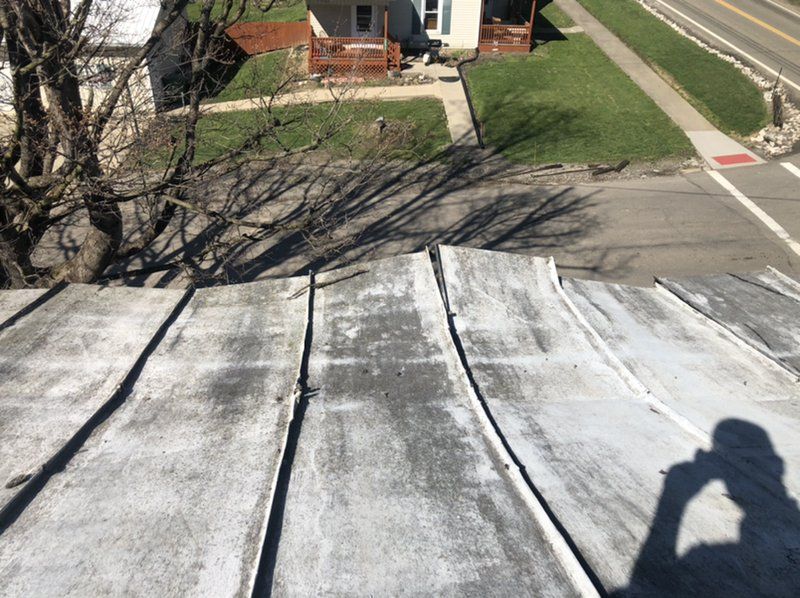 A person is taking a picture of the roof of a house.