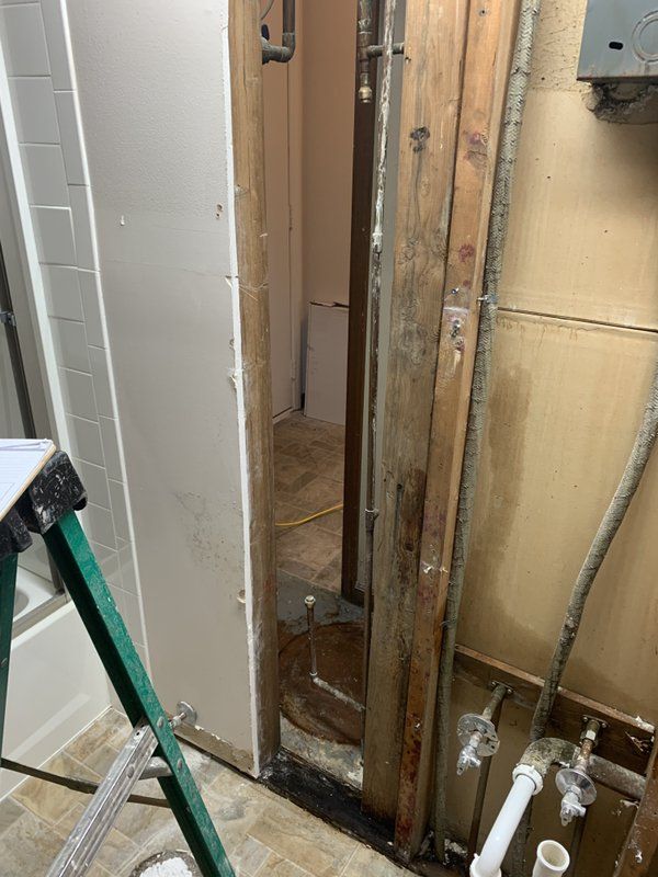 A bathroom with a green ladder and pipes in it.