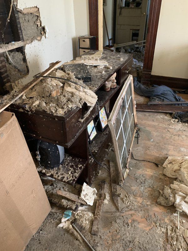 Afire damaged room with a lot of trash on the floor and a desk.