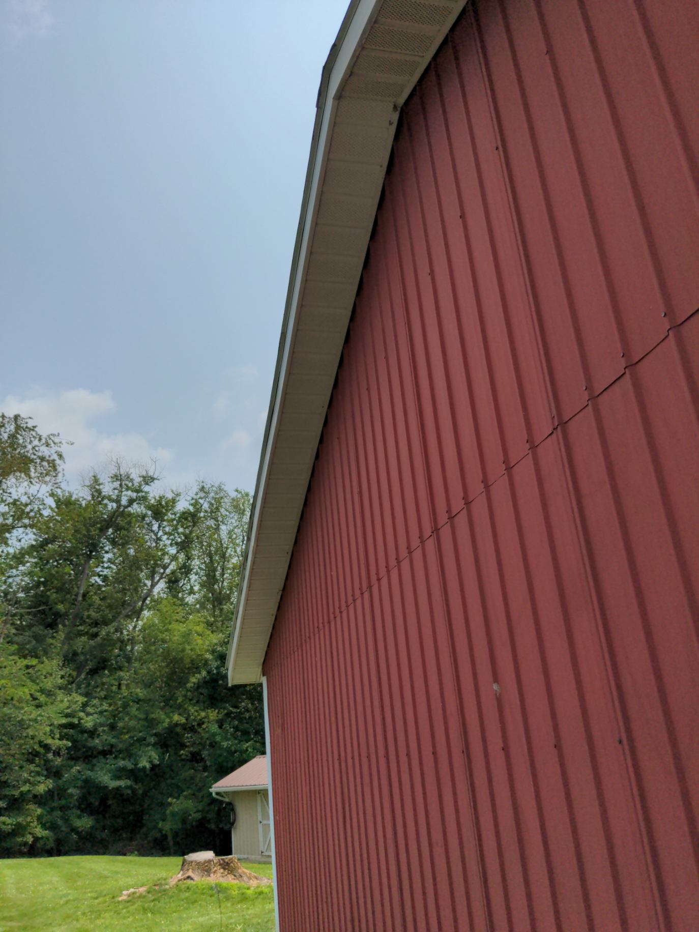 A red barn with a white gutter on the side of it.