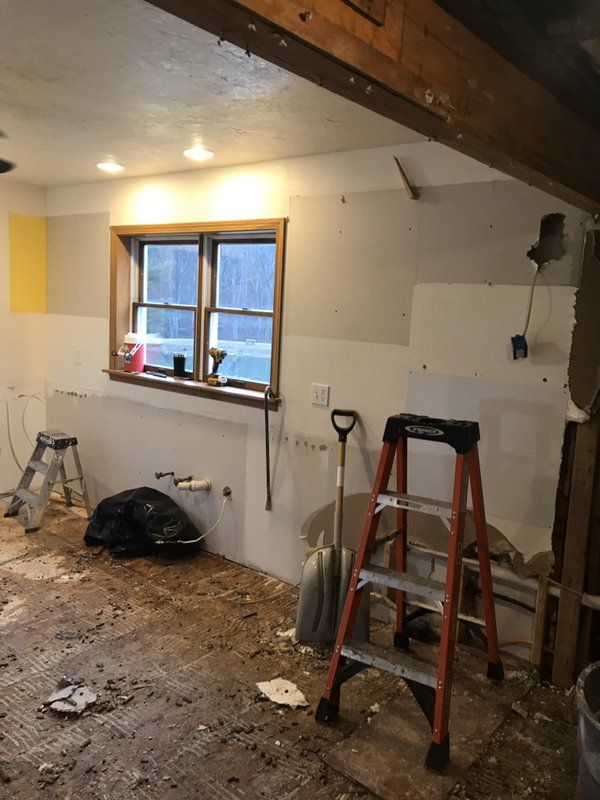 A room being repaired from water damage with tools, ladders, and a window.