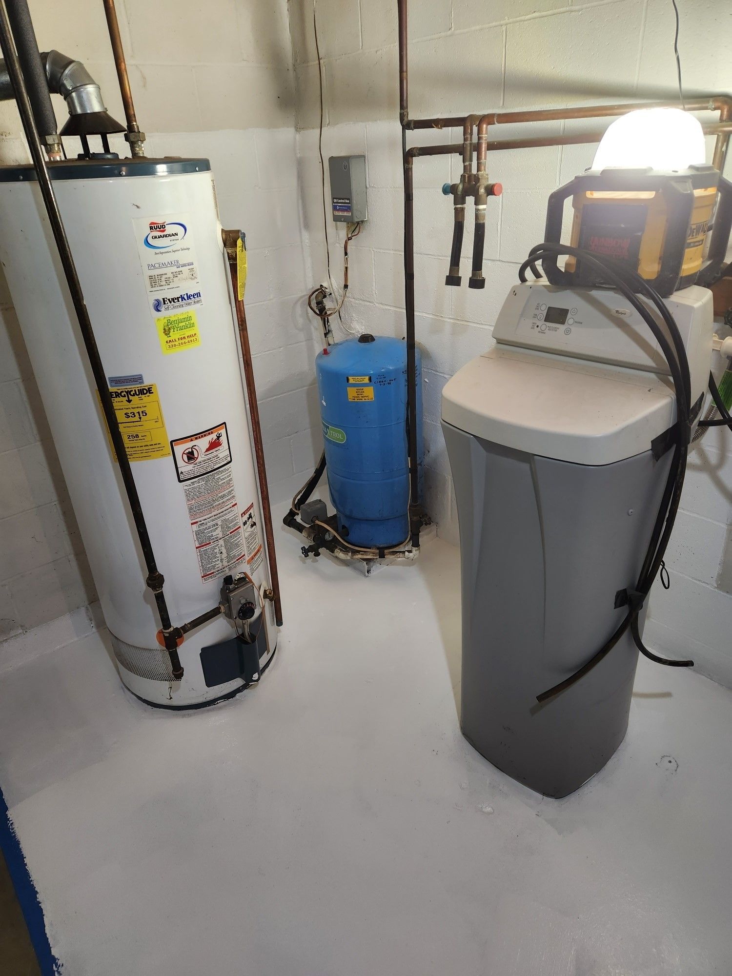 A water heater and a water softener are in a basement.