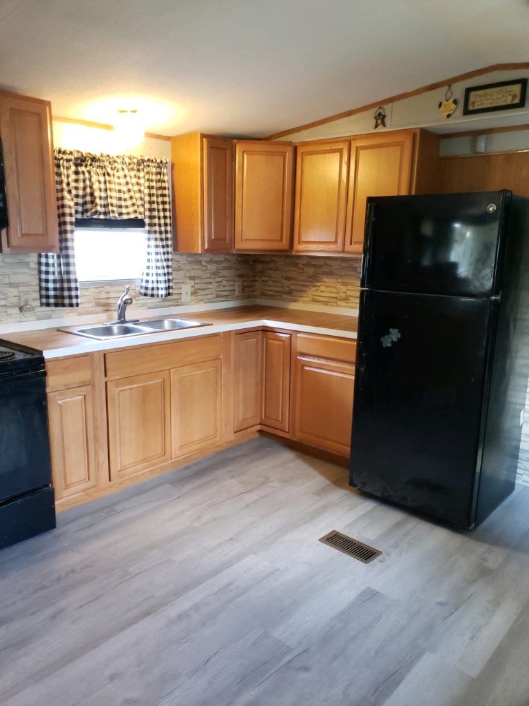 A kitchen with wooden cabinets and a black refrigerator.