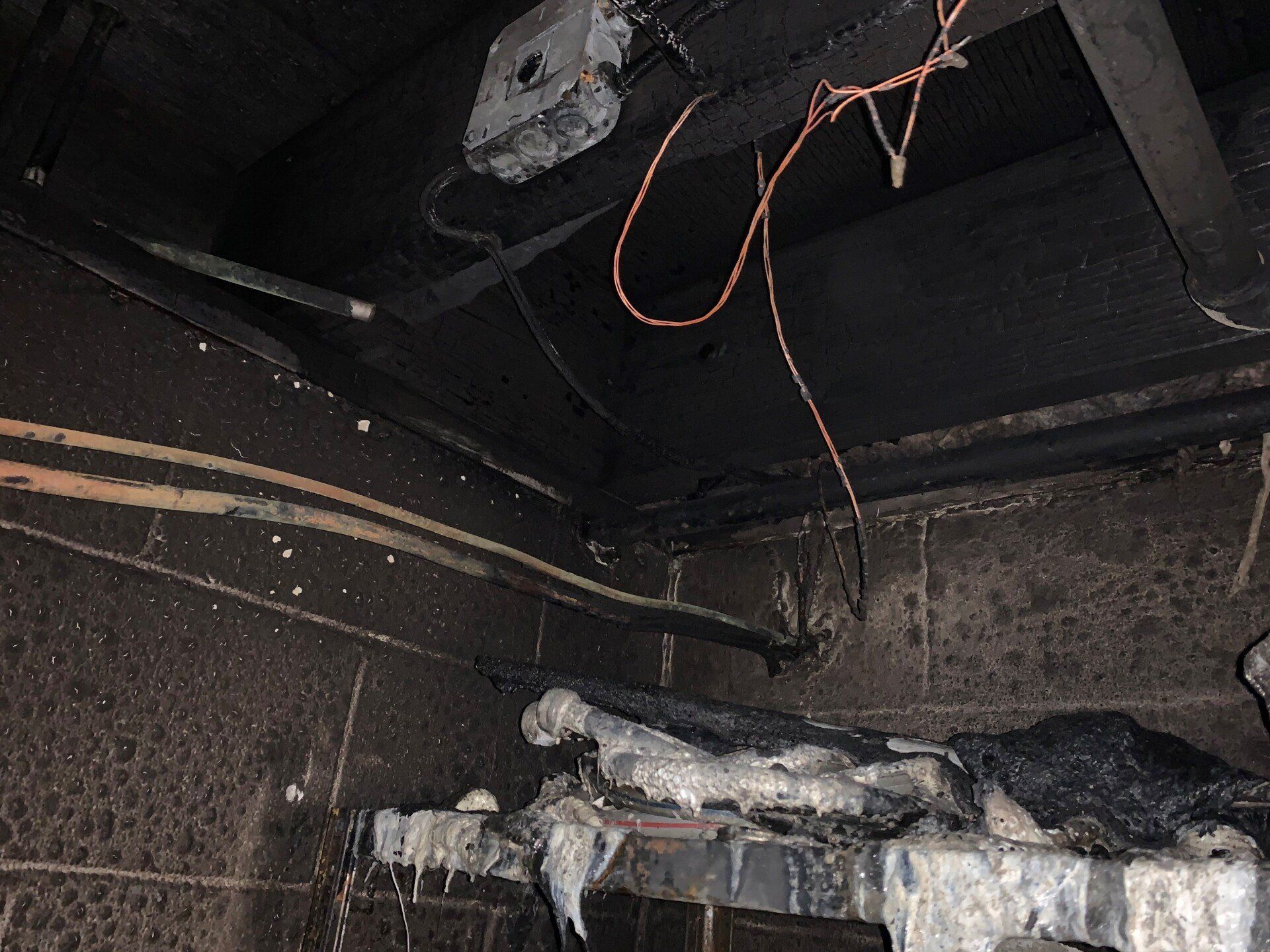 A fire damaged room with a lot of wires hanging from the ceiling.