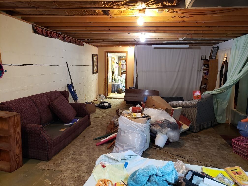 A living room with a couch , chairs , and a vacuum cleaner.