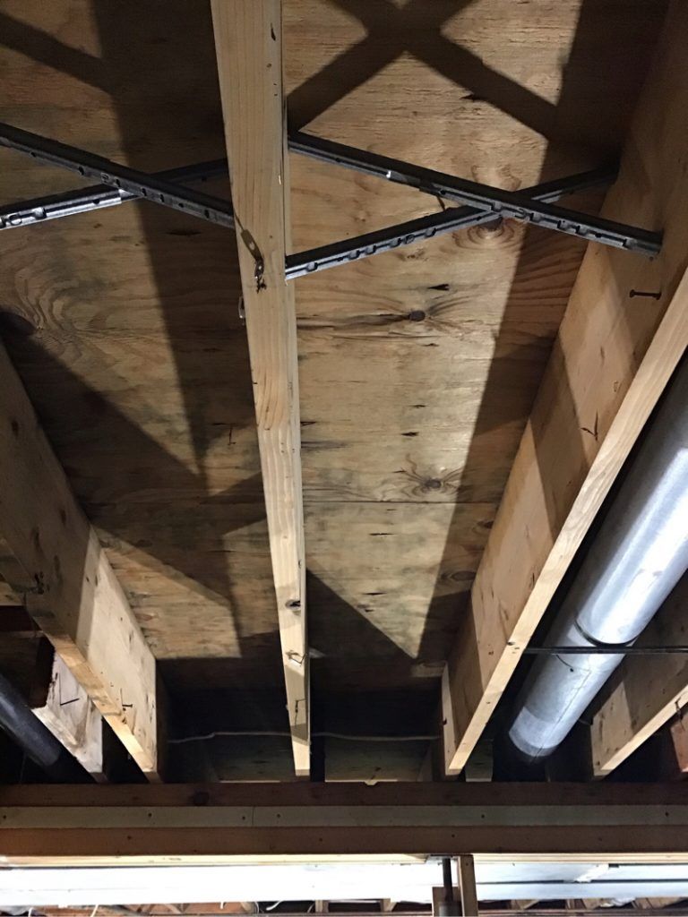 A close up of a ceiling with wooden beams and pipes.