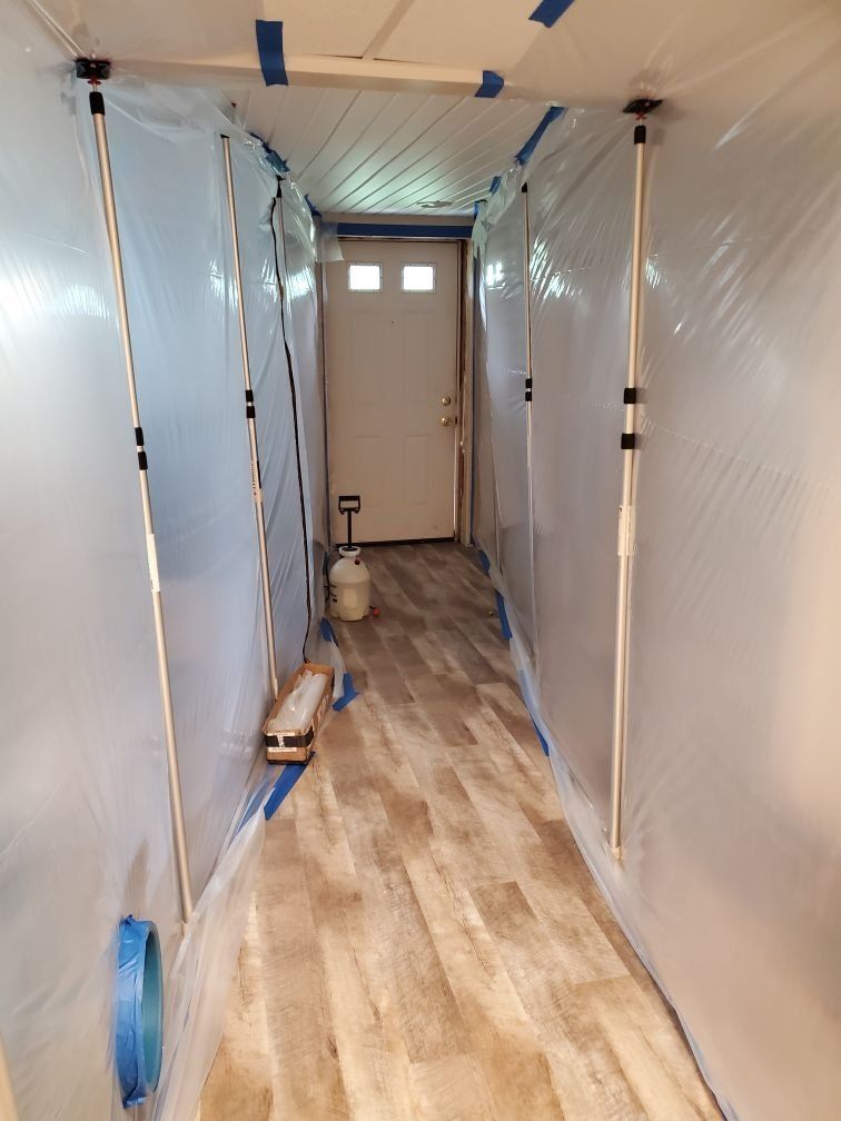 A long hallway covered in plastic sheets and tape.