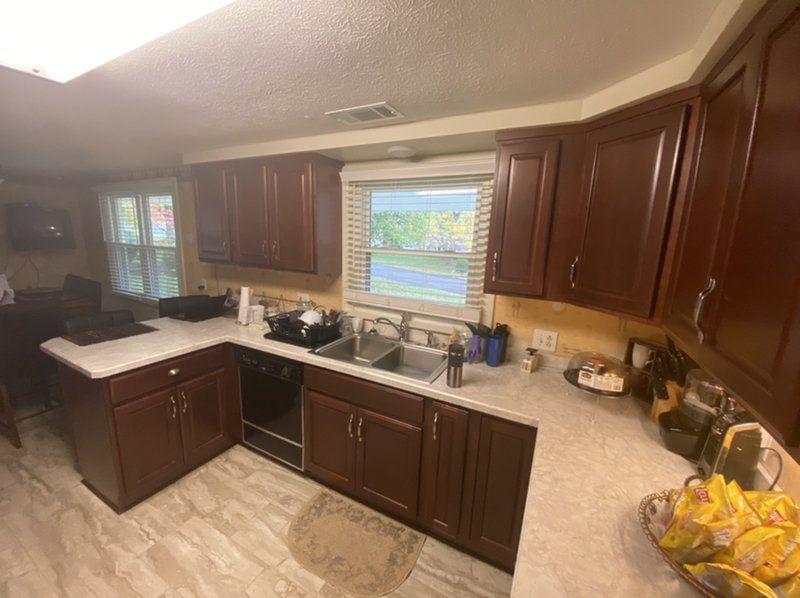 A kitchen with brown wood cabinets , a sink , a stove , and a window.