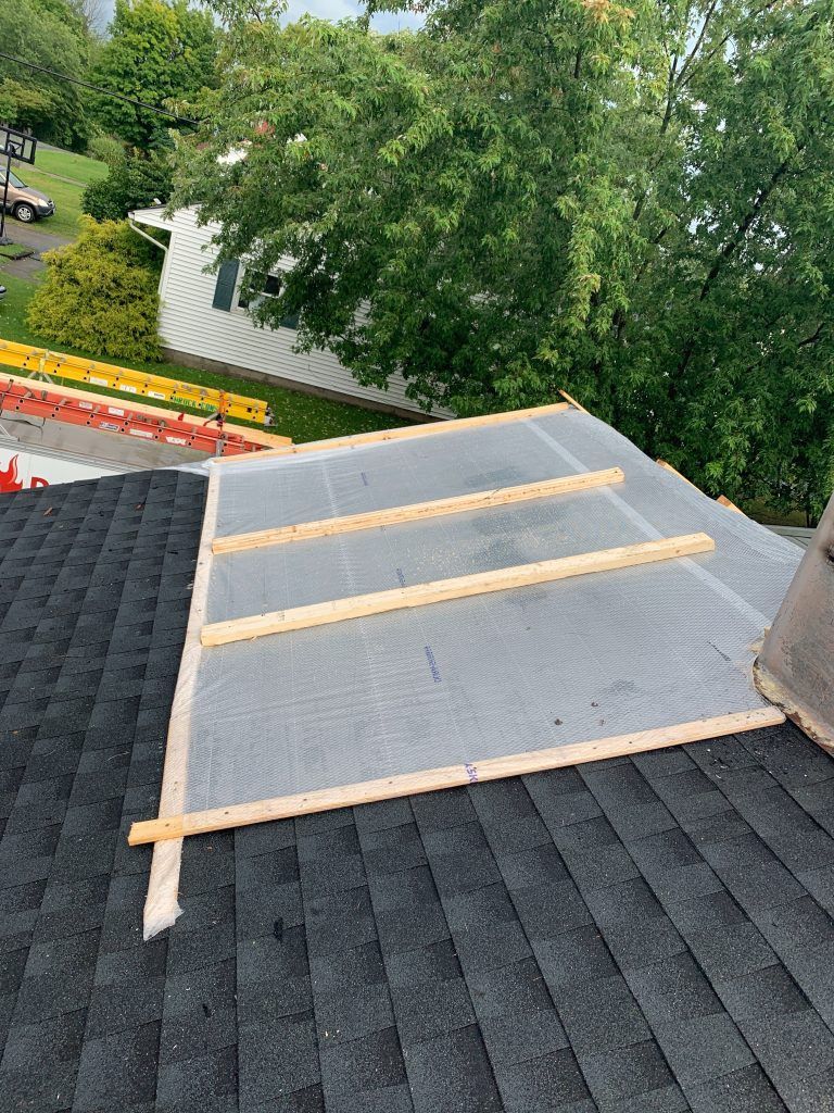 A roof is being rebuilt with wooden beams and shingles.