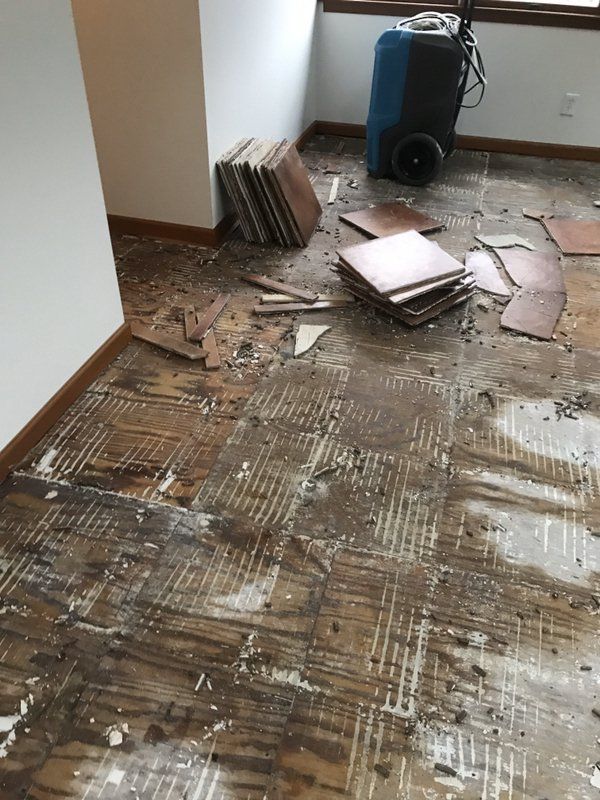 A room with a lot of tiles on the floor and a vacuum cleaner.